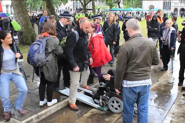 ▲전동 휠체어를 탄 장애인이 경사로를 통해 이동하려 하자 경찰이 이를 가로막고 있다. (유튜브 영상 캡처 ⓒDPAC)