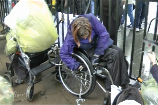 ▲한 시위 참가자가 사원 울타리에 자신의 휠체어를 쇠사슬로 묶고 있다. (유튜브 영상 캡처 ⓒDPAC)