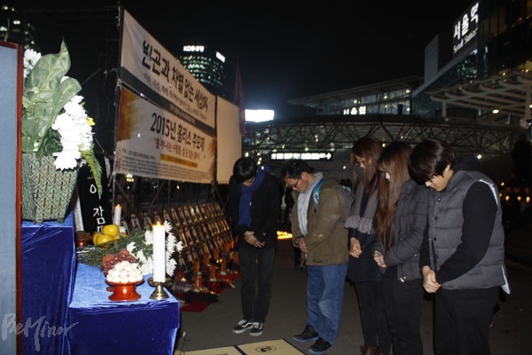거리에서 죽어간 홈리스를 추모하기 위해 마련된 영정 앞에서 묵념하는 사람들