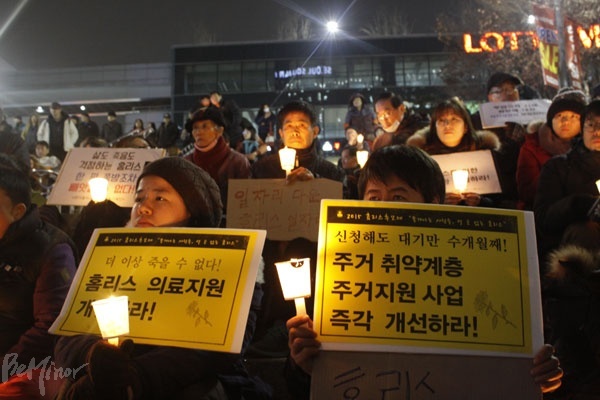 홈리스에 대한 의료와 주거지원을 촉구하는 피켓을 들고 홈리스 추모제에 참여한 사람들 