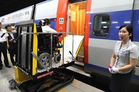 휠체어를 탄 장애인이 휠체어리프트를 이용해 기차에 오르는 모습 