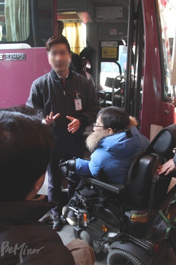 장애인들이 버스를 타지 못하는 것에 항의하자, 버스터미널 직원이 양해를 구하고 있는 모습.