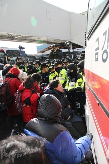 승차장 밑에서 버스의 출발을 막으려는 장애인들과 경찰이 대치하는 모습.