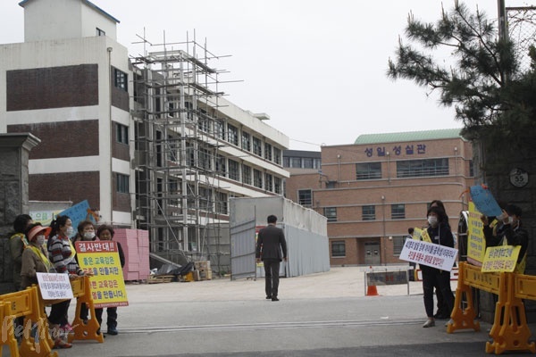 교문 넘어 공사가 일시 중단된 커리어월드 공사 현장이 보인다.