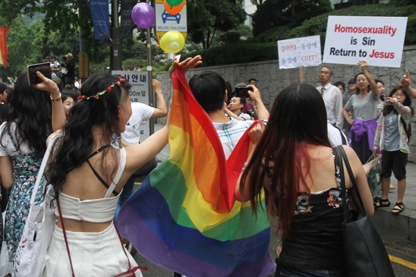 행진 참가자가 '동성애는 죄'라는 피켓을 든 보수 기독교 단체 회원을 두고 오히려 손을 흔들고 있다.
