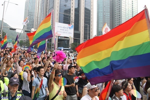 무지개 깃발, 부채 등을 들고 행진하는 참가자들.