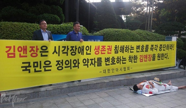 대한안마사협회 소속 시각장애인들이 불법 안마 프랜차이즈 업체 '더풋샵'을 변호하는 로펌회사 김앤장 규탄 시위를 벌이고 있다. 왼쪽에서 현수막을 들고 있는 사람이 김도영 사무총장.