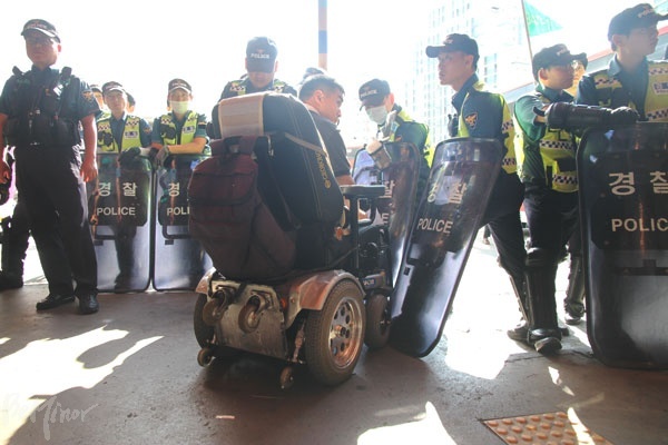 경찰이 승차홈에서 이동하는 휠체어 탄 장애인의 이동을 막아서고 있다. 