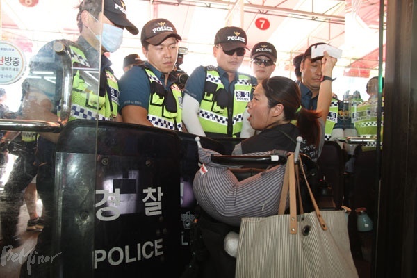 경찰들이 터미널 내부에서 승차홈으로 진입하는 출입구를 막아서자 장애인 활동가가 구매한 표를 들어 보이며 항의하고 있다.