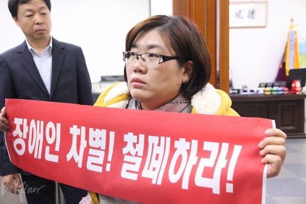 경기장차연 활동가가 이재명 시장이 떠난 시장실 앞에서 피켓을 들고 있는 모습.