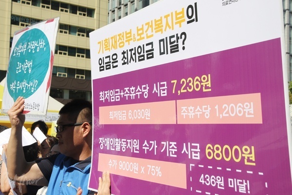 활동보조인들이 활동지원 수가가 법정 최저임금조차 지키지 못하는 상황을 알리고 있는 피켓을 들고 있다. 