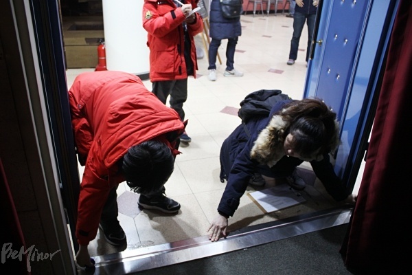 극장 모니터링을 위해 출입구를 줄자로 재고 있는 사람들