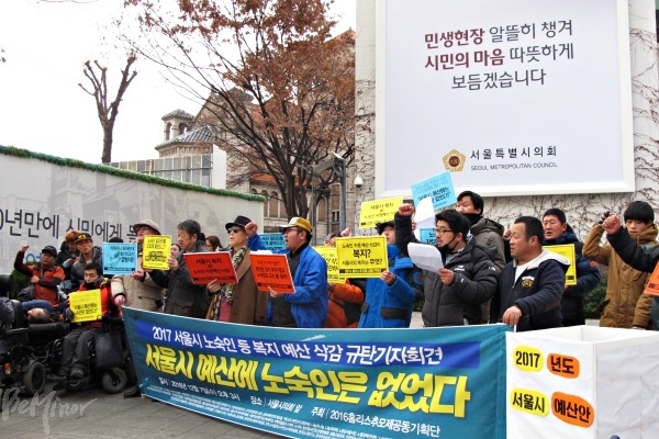 7일 서울시의회 앞에서 노숙인 예산 증가를 촉구하는 기자회견이 진행되고 있는 모습. 서울시의회 건물에 "민생현장 알뜰히 챙겨 시민의 마음으로 따뜻하게 보듬겠습니다"라는 문구가 적힌 현수막이 걸려있다. 