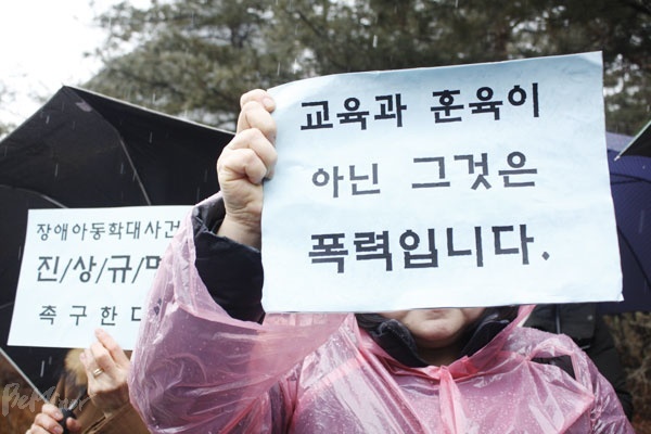 ‘자폐성 장애 전문 대안학교’라는 이름을 걸고 교육과 치료를 명목으로 사실상 장애 유아를 학대해온 용인시 S대안학교 사건과 관련해 장애계가 진상규명을 촉구하며 22일 서울고등법원 앞에서 기자회견을 열었다. 한 기자회견 참가자가 “교육과 훈육이 아닌 그것은 폭력입니다”라는 손팻말을 들고 있다. 