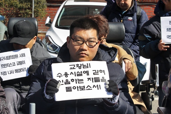 기자회견 참가자가 '교황님! 수용시설에 갇혀 신음하는 자들을 돌아보소서!'라고 쓰인 손팻말을 들고 있다.