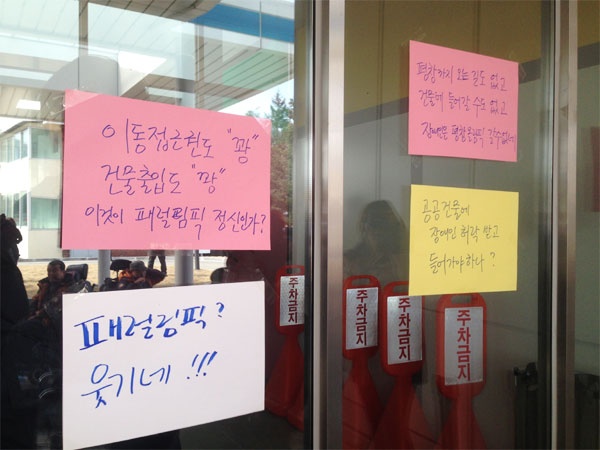 조직위 측에서 화장실 출입을 막자 기자회견 참가자들이 평창동계올림픽 대회조직위원회 사무소 건물에 장애인 이동권 보장과 출입금지를 규탄하는 종이를 붙였다. ⓒ전국장애인차별철폐연대