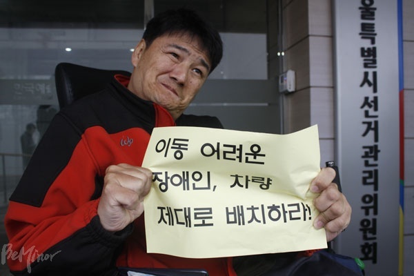 "선거 날 이동 어려운 장애인, 차량 제대로 배치하라" 손피켓을 들고 있는 장애인 활동가  