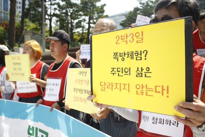 한 참여자가 "2박 3일 쪽방 체험? 주민의 삶은 달라지지 않는다"라고 적힌 피켓을 들고 있다. 