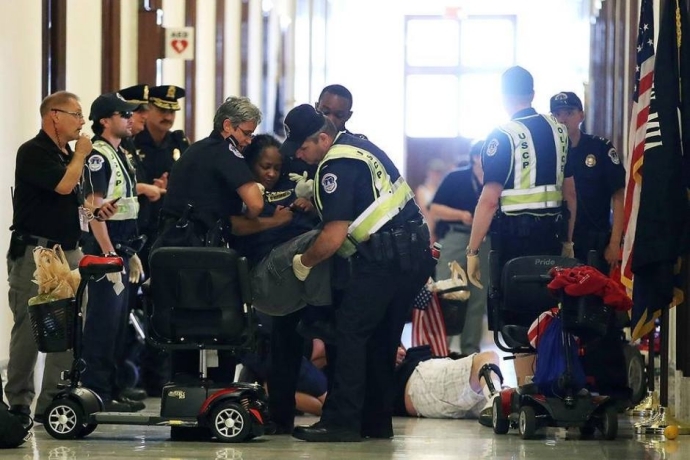 6월 점거 시위 당시 경찰에 의해서 들려 나가고 있는 아니타 캐머론. (사진출처 : National ADAPT 페이스북 페이지)