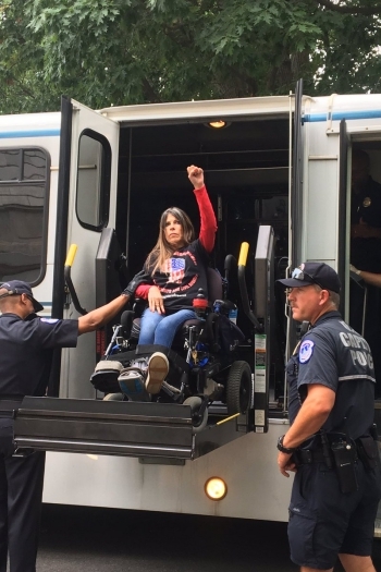 ADAPT 회원 던 러셀이 시위 직후 경찰에 체포되어 조사를 받으러 가기 위해 차에 오르고 있는 모습. (사진출처 : National ADAPT 페이스북 페이지)