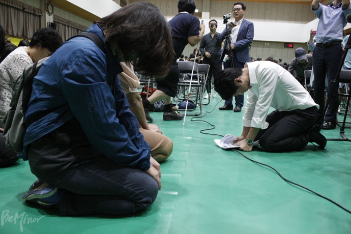 장애부모(왼쪽)가 무릎 꿇자 그 앞에 무릎을 꿇은 반대 측 주민(오른쪽).