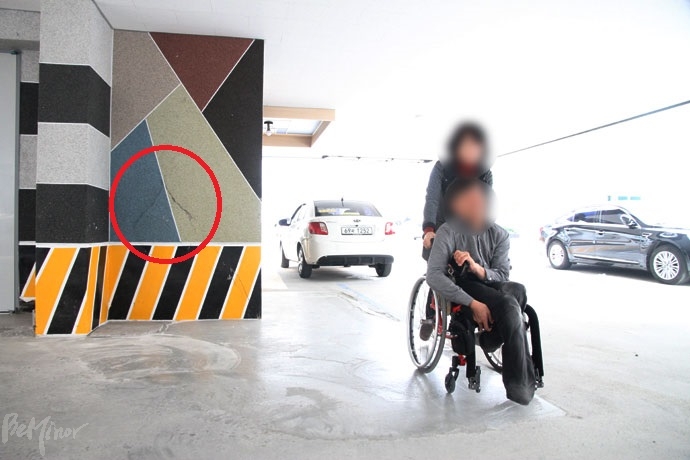 한우진 씨가 활동보조인과 외출하고 있다. 그가 사는 빌라 필로티 내벽에도 커다란 균열(빨간 원)이 가있다. 