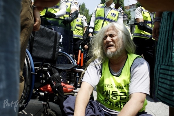 장애등급제 폐지를 요구하며 국무총리 면담 요구 시위를 벌이다 경찰과 충돌, 휠체어에서 떨어져 고통스러워하고 있는 박경석 교장. (2015년 6월 18일)
