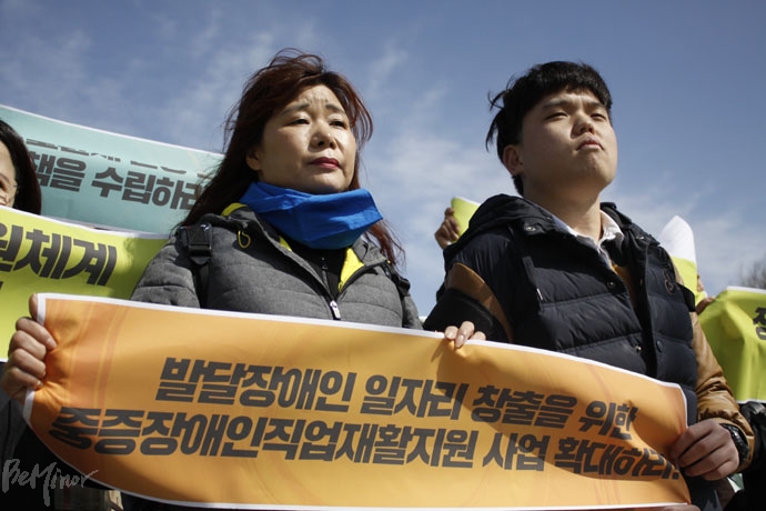 기자회견 참가자 두 명이 '발달장애인 일자리 창출을 위한 중증장애인직업재활지원 사업 확대하라'는 내용의 피켓을 나눠서 들고 있다