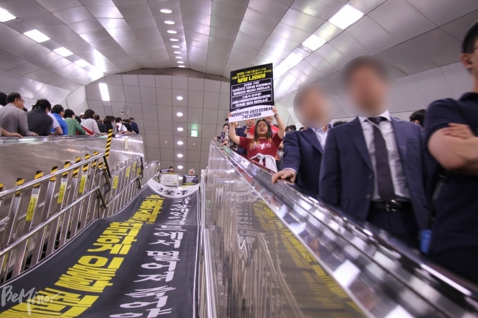 한 활동가가 김태호 사장의 면담을 요구하는 피켓을 들고 에스컬레이터에서 내려오고 있다.