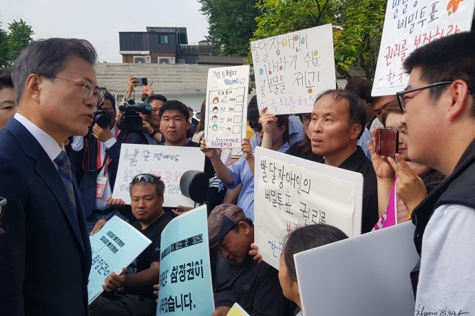 한국피플퍼스트 소속 발달장애인 활동가들이 문재인 대통령에게 발달장애인을 위한 쉬운 공보물과 투표용지 제공의 필요성에 대해 설명하고 있다.(사진=한국피플퍼스트)