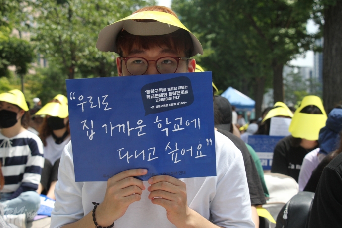 한 참가자가 "우리도 집 가까운 학교에 다니고 싶어요"라고 적힌 손팻말을 들고 있다. 
