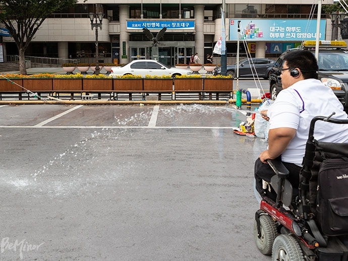 농성장 바닥에서 올라오는 열을 식히기 위해 호스로 물을 뿌리고 있다.