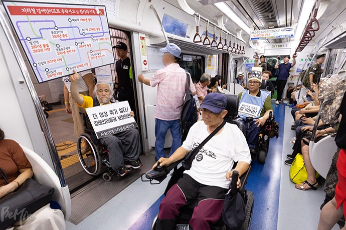 박경석 서울장차연 공동대표가 ‘지하철 장애인리프트 추락사고 및 참사의 기록’이 새겨진 커다란 손팻말을 들고 있다.