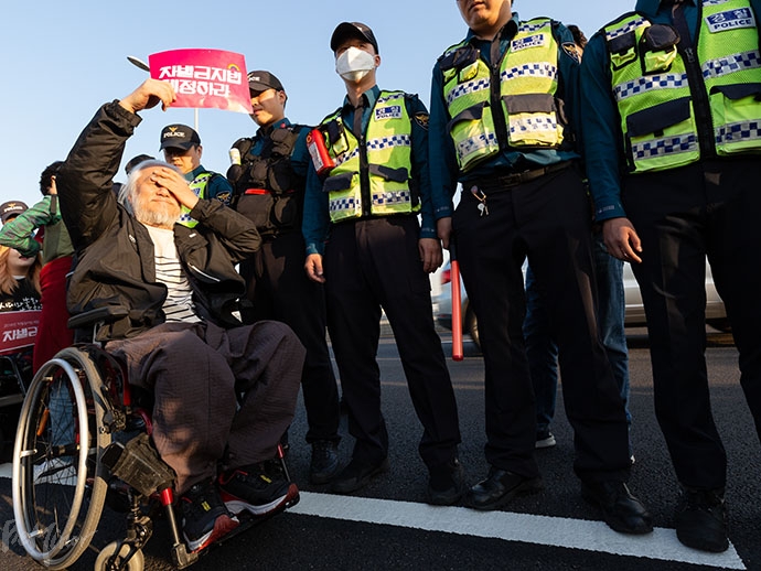 박경석 전국장애인차별철폐연대 상임공동대표가 경찰 앞에서 ‘차별금지법 제정하라’ 손피켓을 들고 있다. 