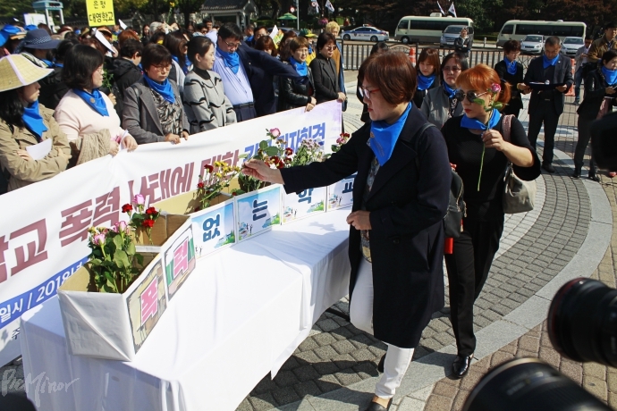기자회견이 끝난 후, 참가자들이 기자회견이 끝난 후, 장애인 부모들이 '폭력 없는 학교'라는 문구가 적힌 상자에 꽃을 넣고 있다.