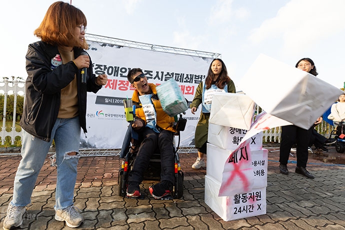 결의대회에서 '가짜 장애등급제 폐지'라는 문구가 적힌 상자들을 무너뜨리는 퍼포먼스를 하고 있다.