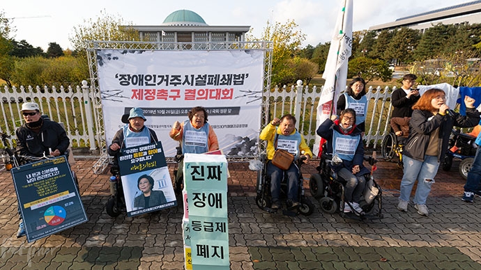 참가자들이 '진짜 장애등급제 폐지'라는 문구가 적힌 상자를 쌓아올린 후 환호하고 있다.