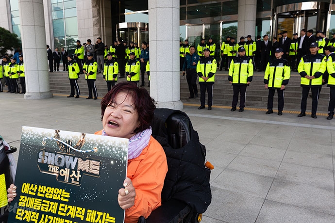 사다리와 쇠사슬을 목에 걸고선 내년도 장애인 복지 예산 확대를 촉구하는 장애인 활동가들. 