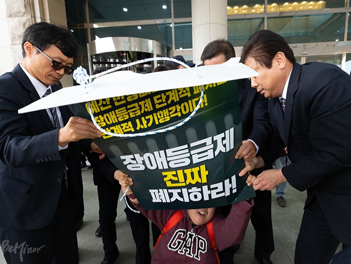 한 활동가가 예산 확보를 촉구하며 피켓을 들자, 이를 빼앗으며 진압하는 국회 보안요원. 