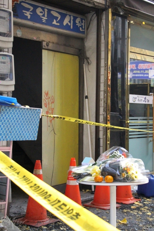 지난 9일, 종로 국일고시원에서 화재로 7명이 사망하고 11명이 부상을 입는 사건이 발생했다. 그 앞에 시민들이 꽃과 과일을 놓아두었다.