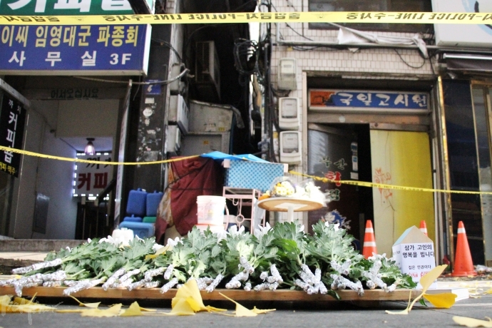 기자회견 참석자들이 헌화한 하얀 국화가 국일고시원 폴리스라인 바깥에 놓였다.