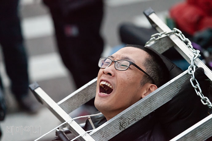 사다리와 쇠사슬로 몸을 결박한 장애인 활동가. 박승원 기자. 사다리와 쇠사슬로 몸을 결박한 장애인 활동가. 박승원 기자.