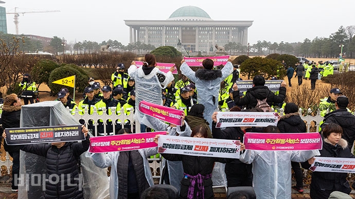발달장애부모들이 국회 담 넘기를 시도하던 중 경찰에 의해 제지당하자 국회를 향해 ‘발달장애 주간활동서비스를 보장하라’는 손팻말을 펼치고 있다. 박승원 기자. 발달장애부모들이 국회 담 넘기를 시도하던 중 경찰에 의해 제지당하자 국회를 향해 ‘발달장애 주간활동서비스를 보장하라’는 손팻말을 펼치고 있다. 박승원 기자.