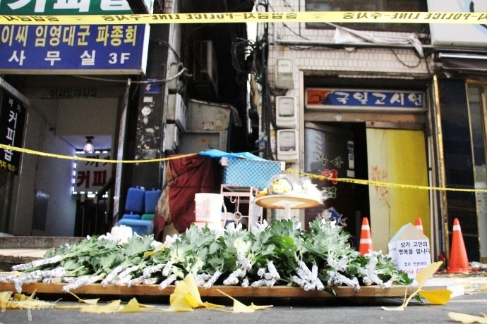 국일고시원 앞에 희생자들을 추모하며 헌화한 흰 국화가 놓여있다. 국일고시원 앞에 희생자들을 추모하며 헌화한 흰 국화가 놓여있다.