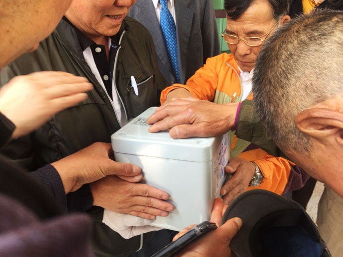 동자동사랑방 주민들이 무연고사망자 장례에 참여해 함께 살던 쪽방 주민의 유골함에 손을 얹고 마지막 인사를 하고 있다 ⓒ나눔과나눔