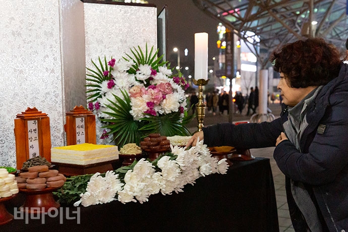 추모제 참석자가 무연고 사망자 영정 앞에 헌화하고 있다.