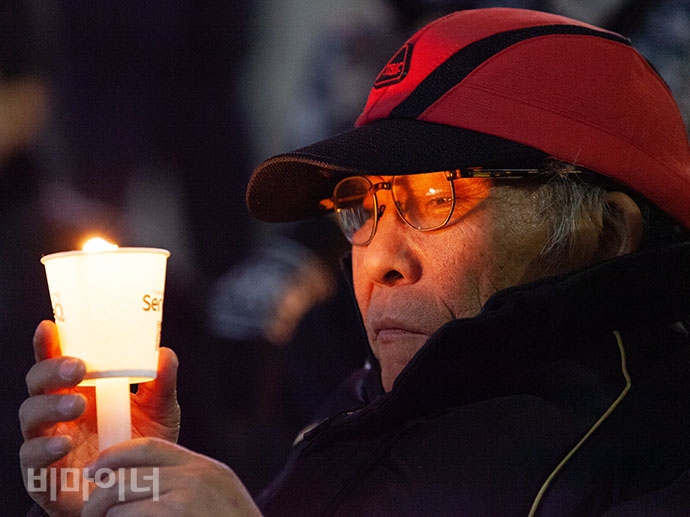 홈리스 쪽방 주민이 바람결에 하늘거리는 촛불을 바라보고 있다.
