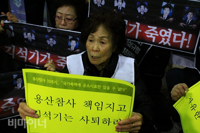 용산참사 유가족 전재숙 씨가 "용산참사 책임지고 김석기는 사태하라"는 손팻말을 들고 있는 모습. 