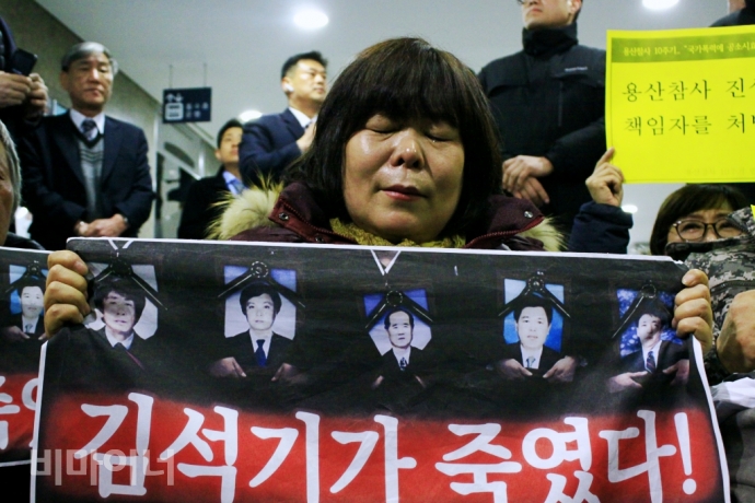 용산참사 유가족 유영숙 씨가 "김석기가 죽였다"라고 적힌 손팻말을 들고 눈물짓고 있다. 