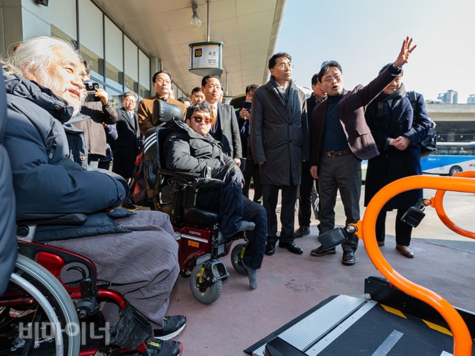박경석 전국장애인차별철폐연대 대표(맨 왼쪽)와 김정렬 국토부 2차관(오른쪽에서 세 번째) 등 휠체어 탑승설비를 갖춘 고속･시외버스 시승행사를 참여한 사람들이 차량을 올려다보고 있는 모습.